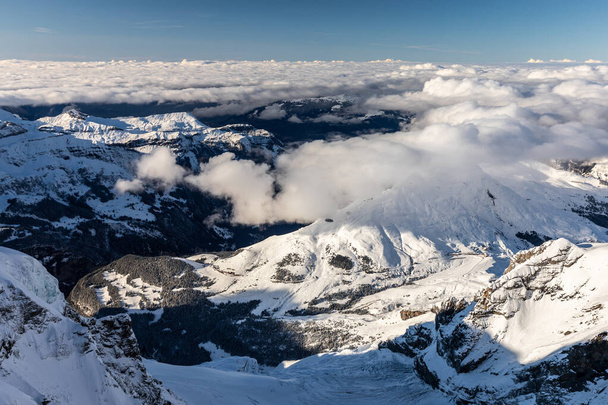 Aerial of snowcapped mountain range of Jungfrau in winter before sunset on cloudy day, view from Jungfraujoch in middle of Jungfrau and Monch, Interlaken, Switzerland. - Foto, afbeelding