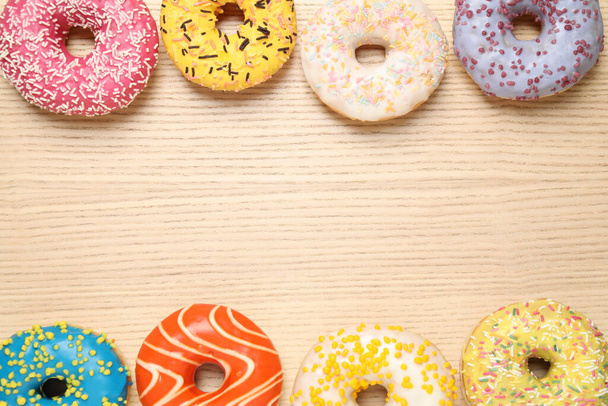 Delicious glazed donuts on wooden table, flat lay. Space for text - Fotoğraf, Görsel