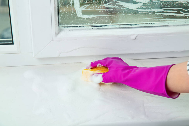 Woman cleaning window sill with sponge indoors, closeup - Fotoğraf, Görsel