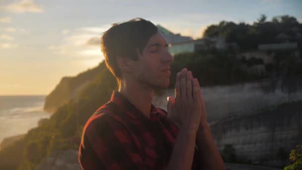Siluetti miehestä, joka rukoilee auringonlaskun aikaan uskonnon käsitettä. Siluetti mies lähellä
. - Materiaali, video
