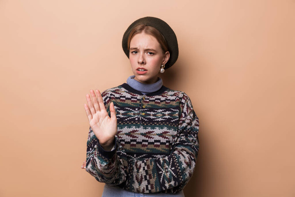 Photo of caucasian displeased woman in earrings making stop gesture isolated over beige background - Photo, Image