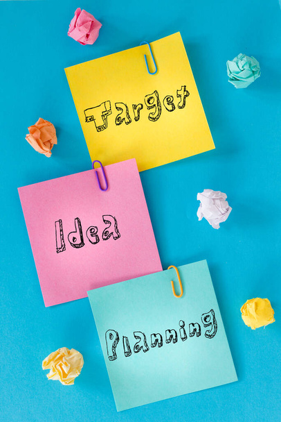  Colorful cards with inscriptions "target, idea, planning" crumpled paper balls, office staples, concept of planning and motivation in business - 写真・画像