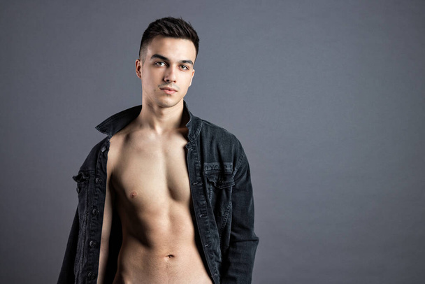 Sexy young man posing in studio. Gray background - Foto, afbeelding