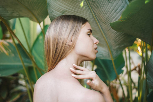 ウェルネスとボディケアの概念。自然の化粧と植物を背景に熱帯性の自然の中で健康な肌を持つ穏やかな若い大人の女の子のバックビュー - 写真・画像