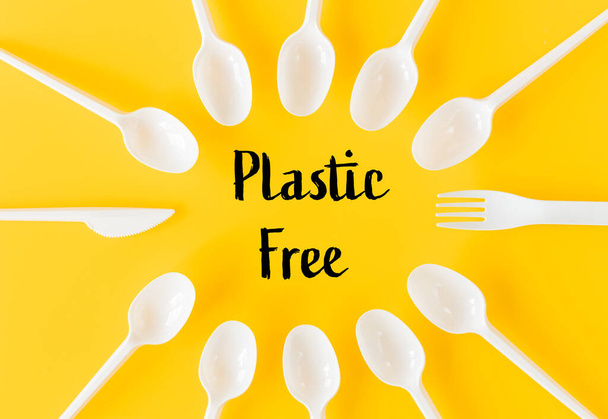 White, plastic disposable cutlery on a yellow background.  The inscription "Plastic Free" The concept of reducing the amount of artificial materials on earth - Photo, Image