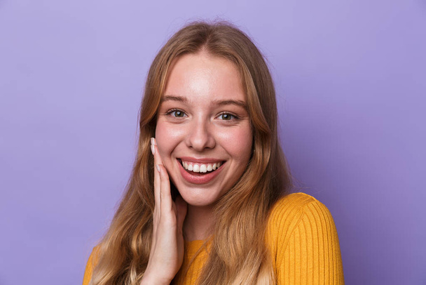 Photo of happy young woman smiling and looking at camera isolated over blue background - Foto, immagini