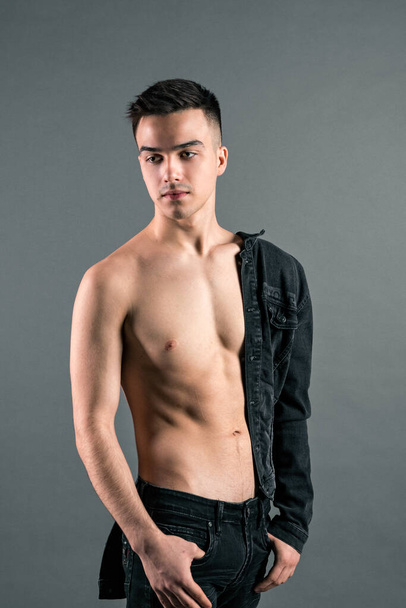 Sexy young man posing in studio. Gray background - Фото, изображение