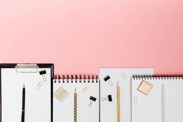 Planificador de burlas plano laico, vista horizontal superior fondo rosa. Bloc de notas y cuadernos con papelería. Oro, blanco, rosa y negro c
 - Foto, imagen