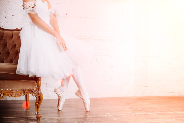Ballet dancer's feet on studio floor. Teenage dancer puts on ballet pointe shoes. Elegance and balance concept top horizontal view - Photo, Image
