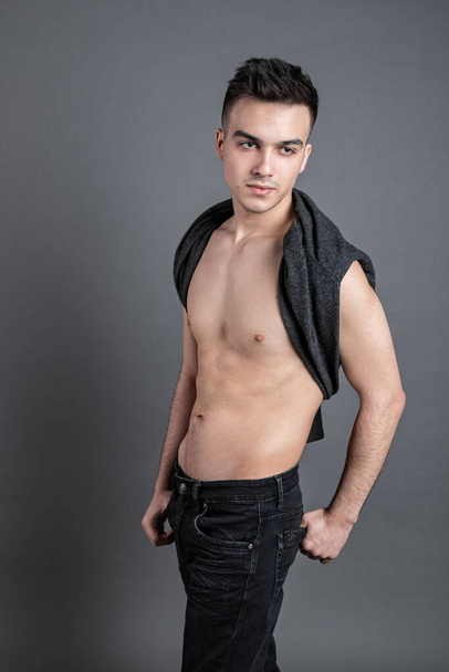 Sexy junger Mann posiert im Studio. Grauer Hintergrund - Foto, Bild