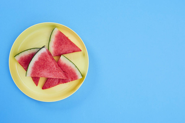 fresh slices of ripe watermelon in yellow plate on blue background. Super Summer Sale Banner, Healthy food, Summertime.  copy space for text - Fotó, kép