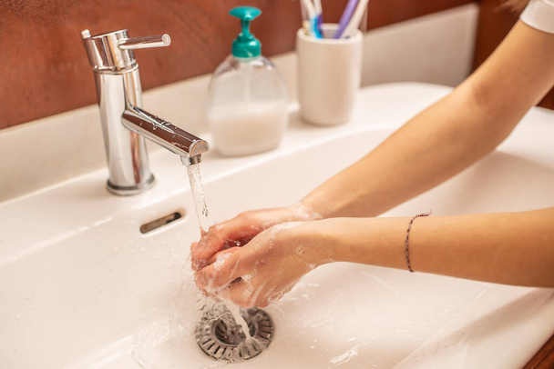 Washing hands with water and liquid soap in the bathroom - Фото, зображення