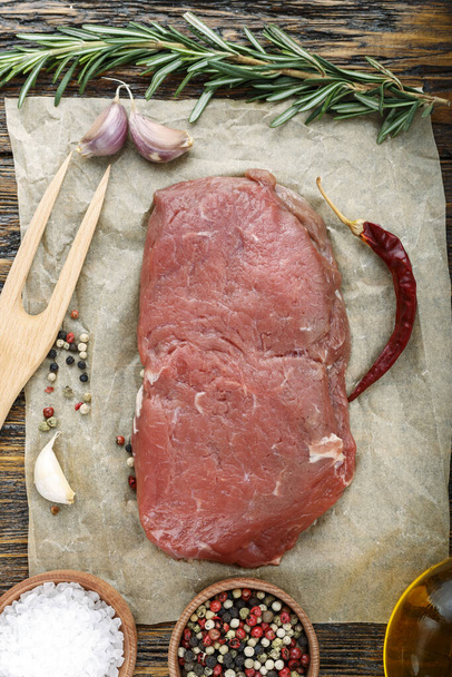 raw steak on a wooden background, on craft paper. meat for grilling or barbecue. place for tex - Foto, imagen