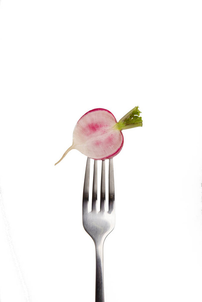 Meio rabanete em garfo com o meio rosa em fundo branco
 - Foto, Imagem