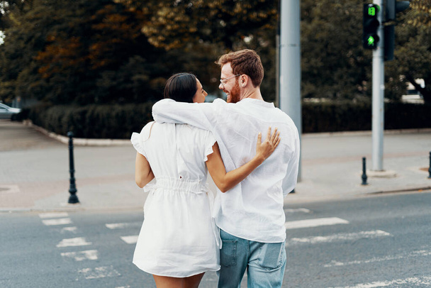 Verliebte Paare spazieren durch die Stadt. glücklich, zusammen zu sein. schönes junges Paar hält Händchen und schaut einander lächelnd an, während es durch die Straßen der Stadt geht - Foto, Bild
