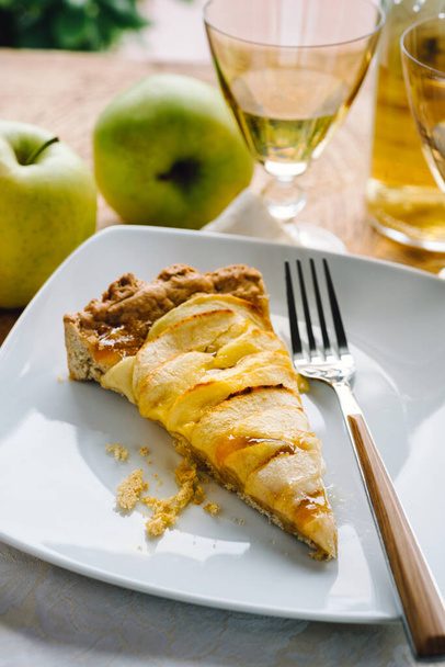 A slice of homemade apple tart on white plate on the table - Photo, image