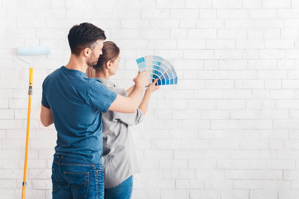 Young couple choosing blue color on palette for painting walls - Foto, immagini