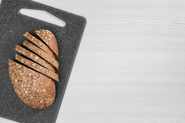 Bread with seeds and flakes on grey board on white background. - Foto, imagen