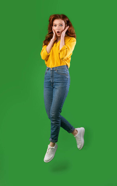 Shocked Girl Jumping Cupping Face In Hands Over Green Background - Foto, Imagem