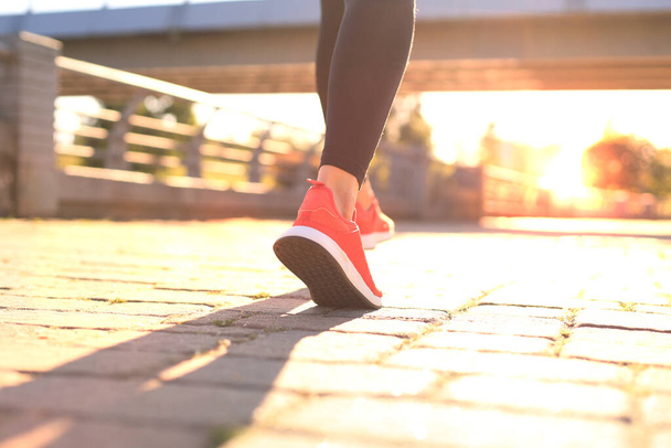 Close up of young woman in sports shoes jogging while exercising outdoors - Foto, afbeelding