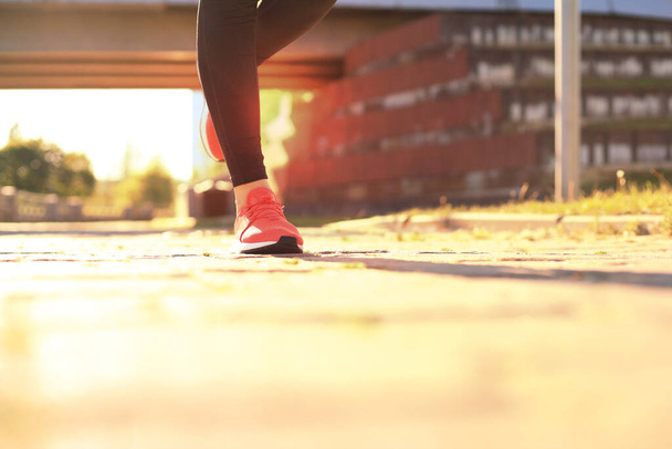Close up de jovem mulher em sapatos esportivos jogging enquanto se exercita ao ar livre
 - Foto, Imagem