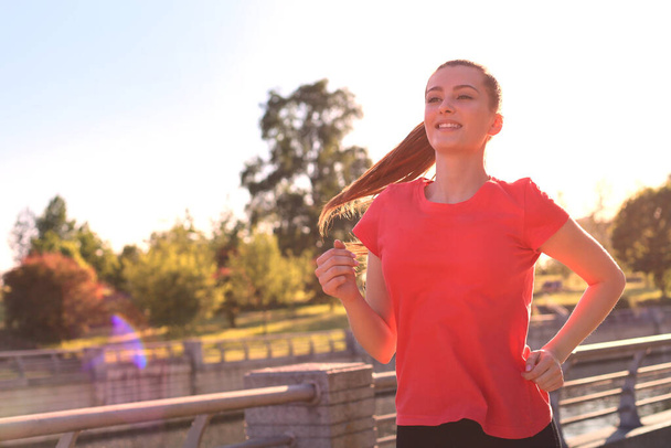 Krásná mladá žena ve sportovním oblečení, která běží během cvičení venku - Fotografie, Obrázek