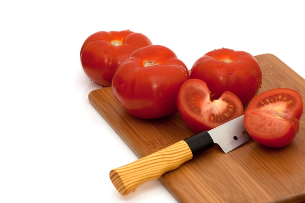 Sliced and whole tomatoes and knife on breadboard - Fotoğraf, Görsel