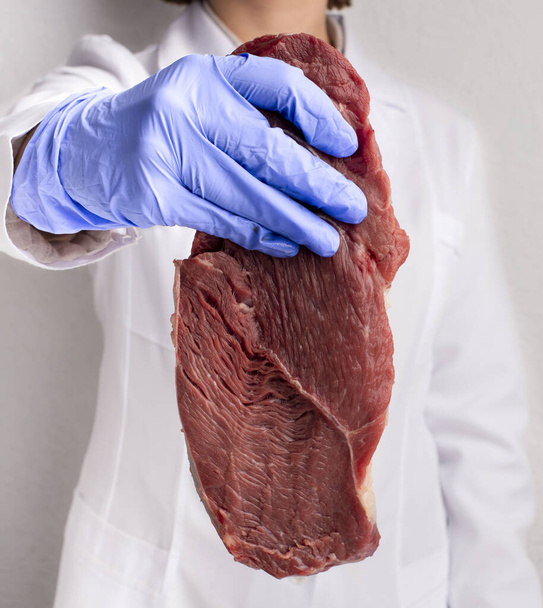 Ученый в перчатках держит сырое мясо, обрезанное
 - Фото, изображение