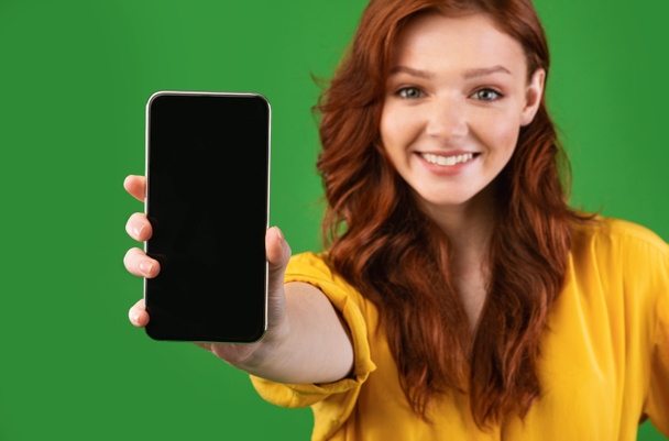 Dziewczyna Wyświetlanie Smartphone pusty ekran aplikacja reklamowa, zielone tło - Zdjęcie, obraz