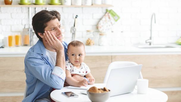 Tired dad working with baby son at home kitchen - Foto, imagen