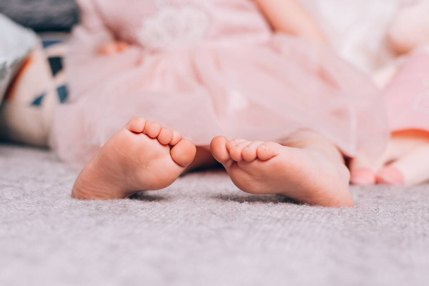Mignon petit enfantss pieds nus couchés sur une couverture tricotée chaude avec un jouet doux. Temps confortable à la maison, style de vie
. - Photo, image