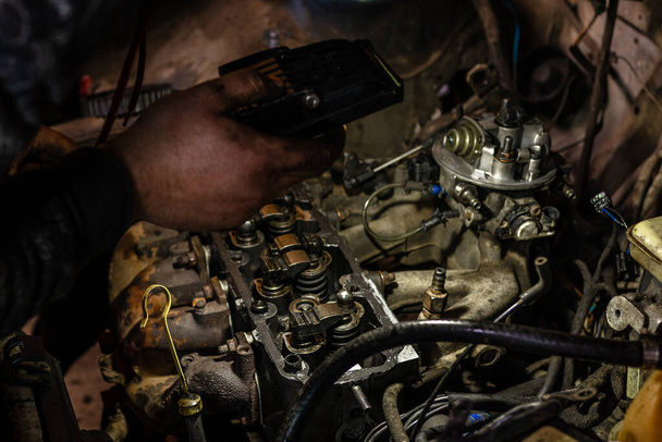 Un mécanicien allume une lampe de poche sur un moteur défectueux dans un service automobile pour identifier les problèmes 2020
 - Photo, image