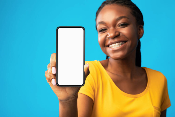 Menina mostrando Smartphone tela em branco sobre azul estúdio fundo, Mockup
 - Foto, Imagem
