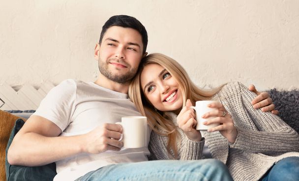 Handsome guy and his girlfriend with hot drinks spending time together at home, panorama - Foto, Bild