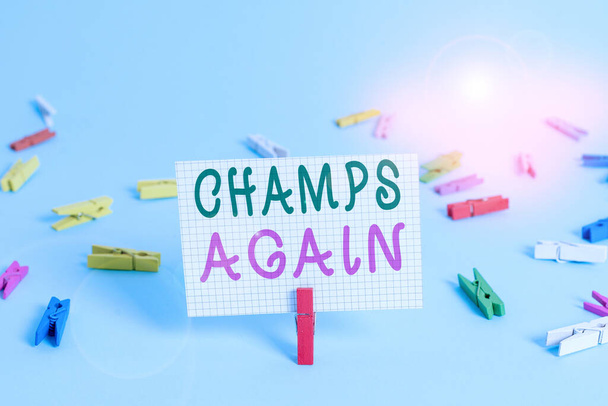 Text sign showing Champs Again. Conceptual photo refers to winner or someone who excels and enjoys victories Colored clothespin rectangle square shaped paper light blue background. - Foto, Bild