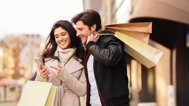 Jeune couple utilisant le téléphone après avoir fait du shopping dans le centre commercial
 - Photo, image