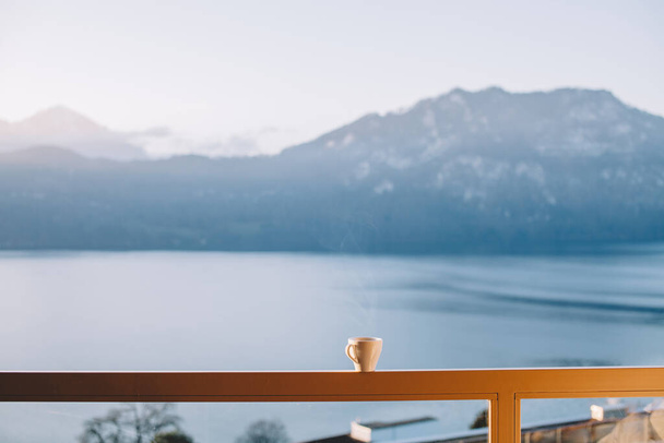 φλιτζάνι καφέ στο τραπέζι βεράντα με θέα στη λίμνη και το βουνό στην Ελβετία - Φωτογραφία, εικόνα