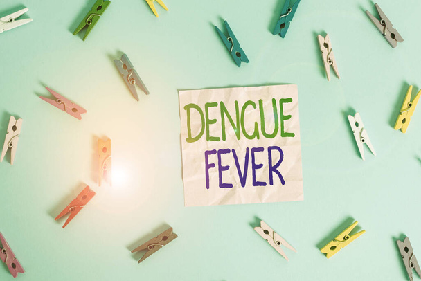 Text sign showing Dengue Fever. Conceptual photo infectious disease caused by a flavivirus or aedes mosquitoes Colored clothespin rectangle shaped reminder paper light blue background. - Photo, Image