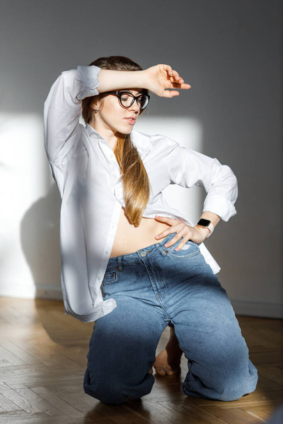 Indoor portrait of fashionable woman wearing wide jeans and glasses. Pretty girl have fun in studio. Fashion blogger concept. Spring fashion concept. beautiful model. home alone - Valokuva, kuva