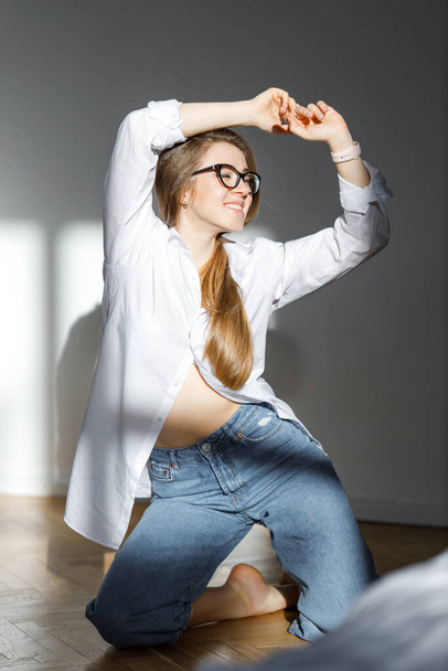 Indoor portrait of fashionable woman wearing wide jeans and glasses. Relaxed happy woman. Pretty girl have fun in studio. Fashion blogger concept. Spring fashion concept. beautiful model - Photo, Image