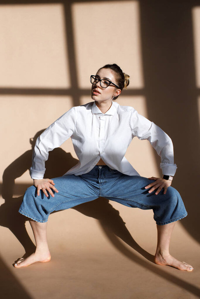 Indoor portrait of fashionable woman wearing wide jeans and glasses. Pretty girl have fun in studio. Fashion blogger concept. Spring fashion concept. beautiful model - Фото, зображення