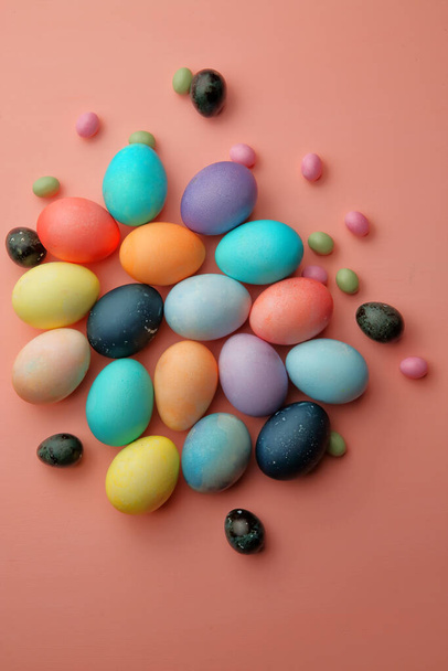 Bunte Eier und Bonbons liegen auf rosa Hintergrund. - Foto, Bild