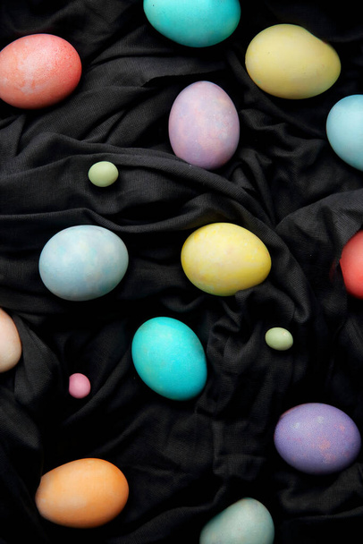 Барвисті яйця і льодяники на чорному тлі, Великдень
. - Фото, зображення
