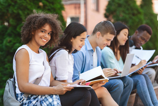 negro estudiante chica preparación para exámenes al aire libre con su universidad amigos
 - Foto, imagen