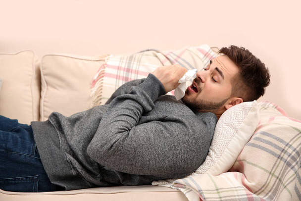 Kranker junger Mann niest zu Hause. Grippeviren - Foto, Bild