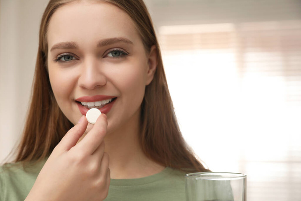 Young woman taking vitamin pill at home - Foto, Imagem
