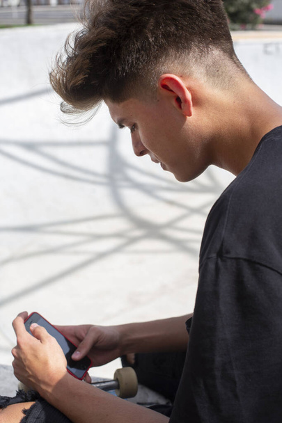 Jeune skateboarder tapant sur son téléphone portable
 - Photo, image