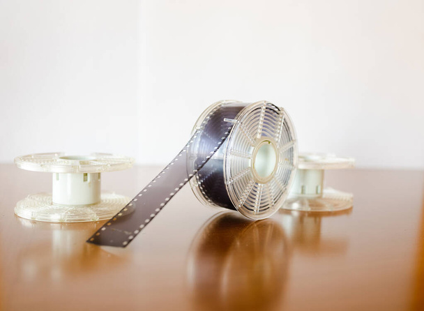 暗室で35ミリフィルムを開発するためのキット。白い背景のテーブルの上のフィルムリールとフィルムタンク. - 写真・画像
