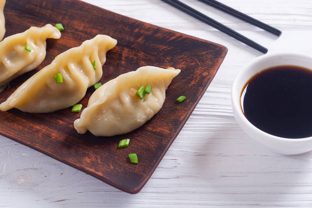 Traditional asian dumplings gyoza with green onion and soy sauce - Foto, afbeelding