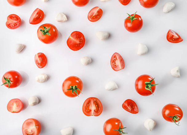 Dojrzałe czerwone pomidory wiśniowe i mozarella na białym tle. Układy płaskie - Zdjęcie, obraz